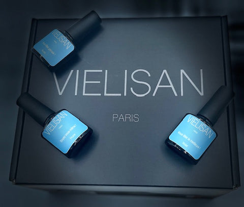 3 flacons noir étiquettes bleues vernis semi-permanent 10 ml VIELISAN vu de haut, allongés sur boîte noire VIELISAN pack le premium