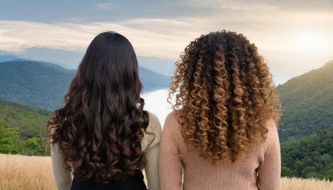 deux femmes de dos face à la nature, l'une avec des cheveux bouclés, la seconde aux cheveux secs