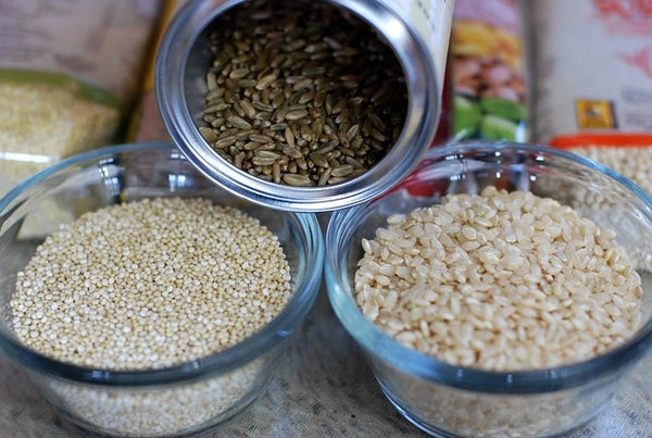 Trois variétés de graines dans des bols transparents : quinoa, graines de tournesol et riz, présentés comme des sources possibles de magnésium