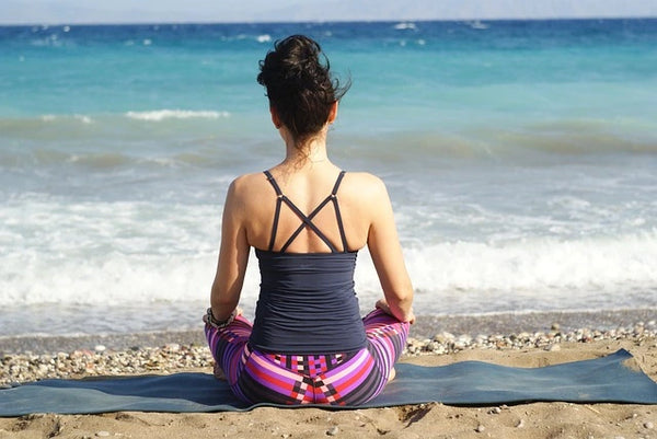 femme méditant fâce à la mer pour créer une routine de relaxation et mieux gérer le stress au quotidien