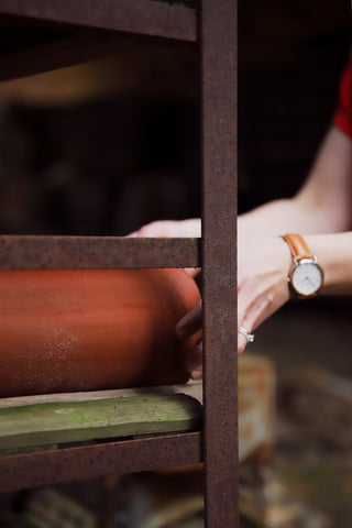 A brick pipe on a shelf and the hands of Ehea Living's founder Tiina Roos holding it in an old factory environment.