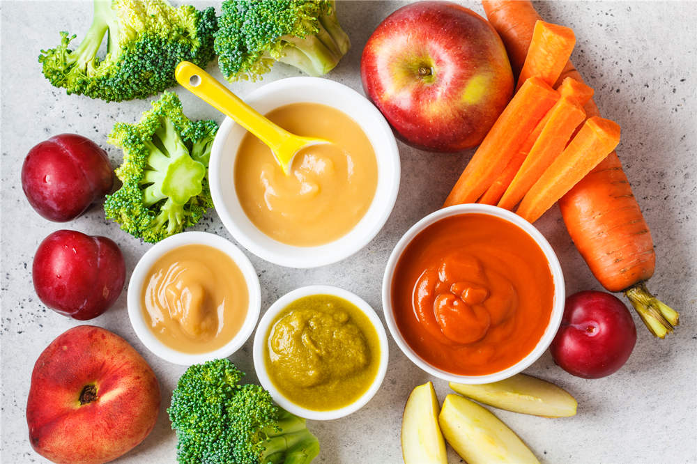 Vegetable and fruit baby puree in white bowls with ingredients