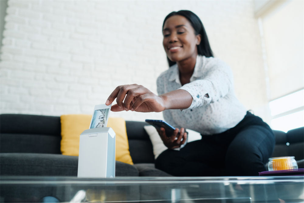 Black woman printing pictures with portable wireless mini printer at home