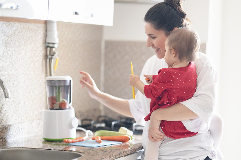 Mother is showing a blender to her little daughter