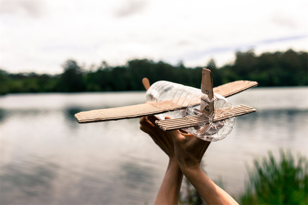 children's hands playing with a plane built with recycled material