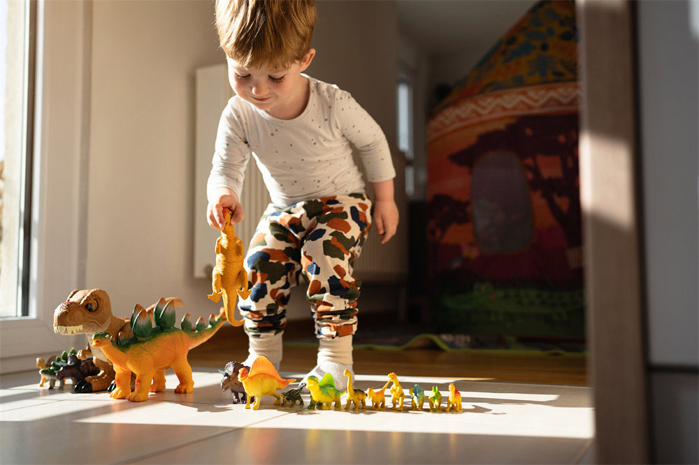 Caucasian toddler boy playing with dinosaur toys