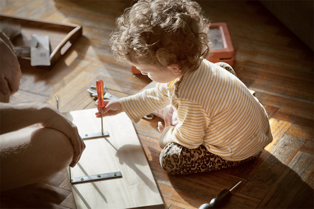 Little girl turns a screw using a screwdriver