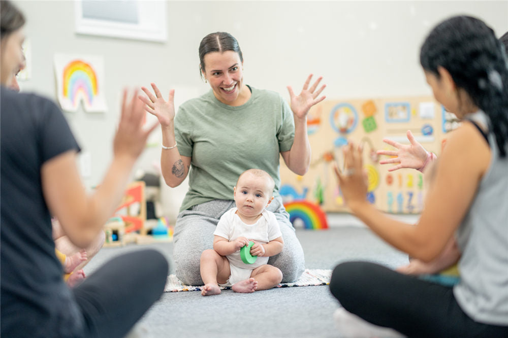 A small group of parents and their babies, participate in a sign language class together