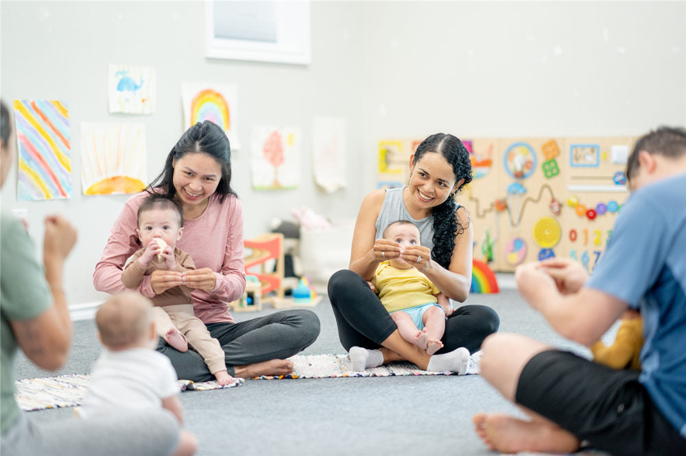 A small group of parents and their babies, participate in a sign language class together