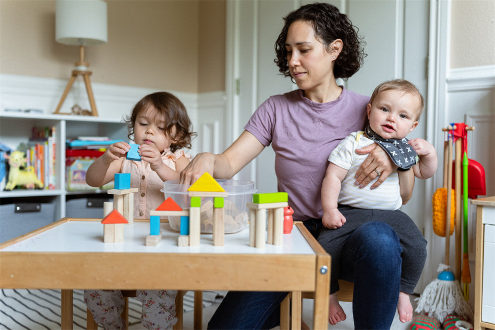Mom and two kids building with wooden block in playroom