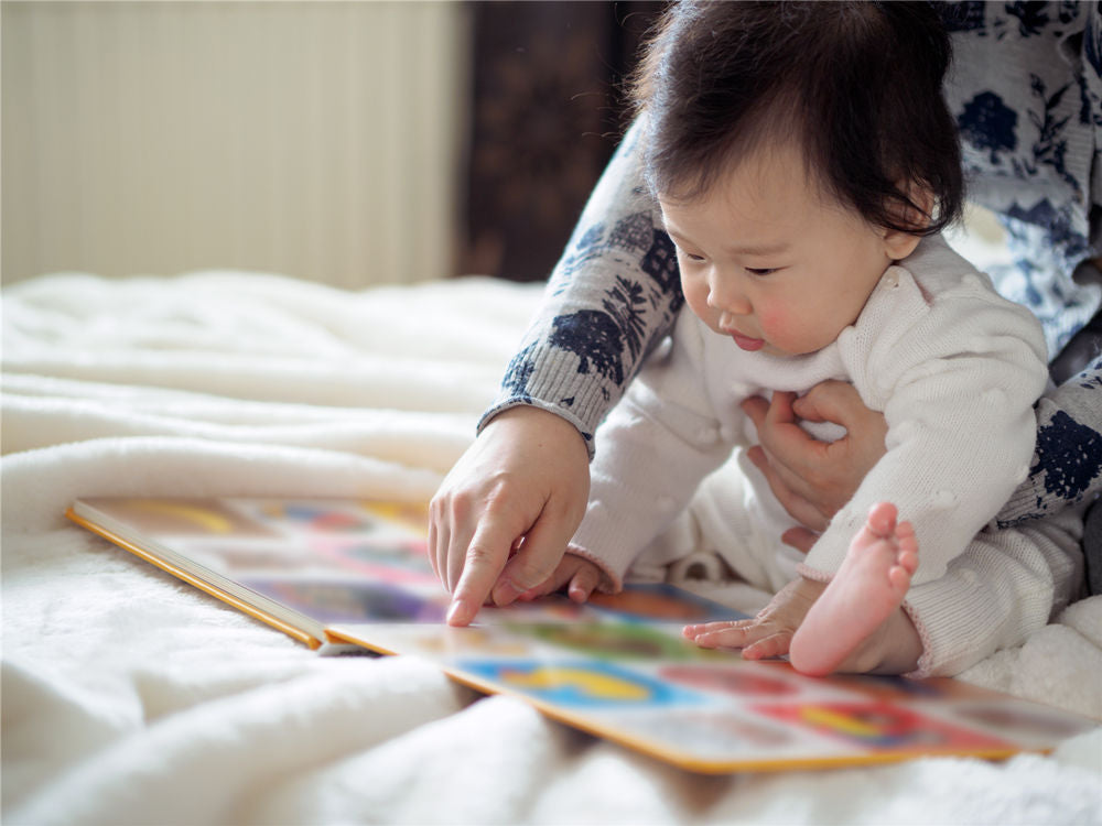 Baby girl reading book with mom