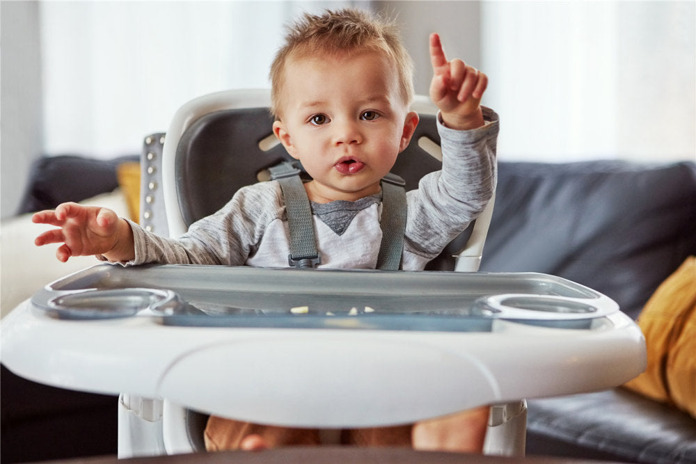 a cute little baby boy sitting in his feeding chair