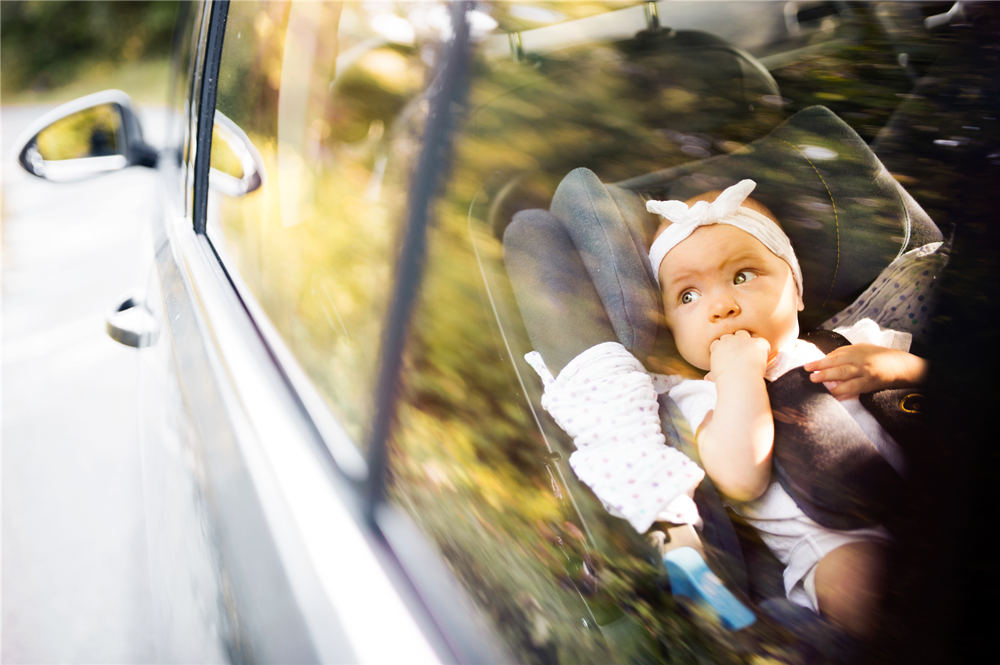 Little baby fastened with security belt in safety car seat