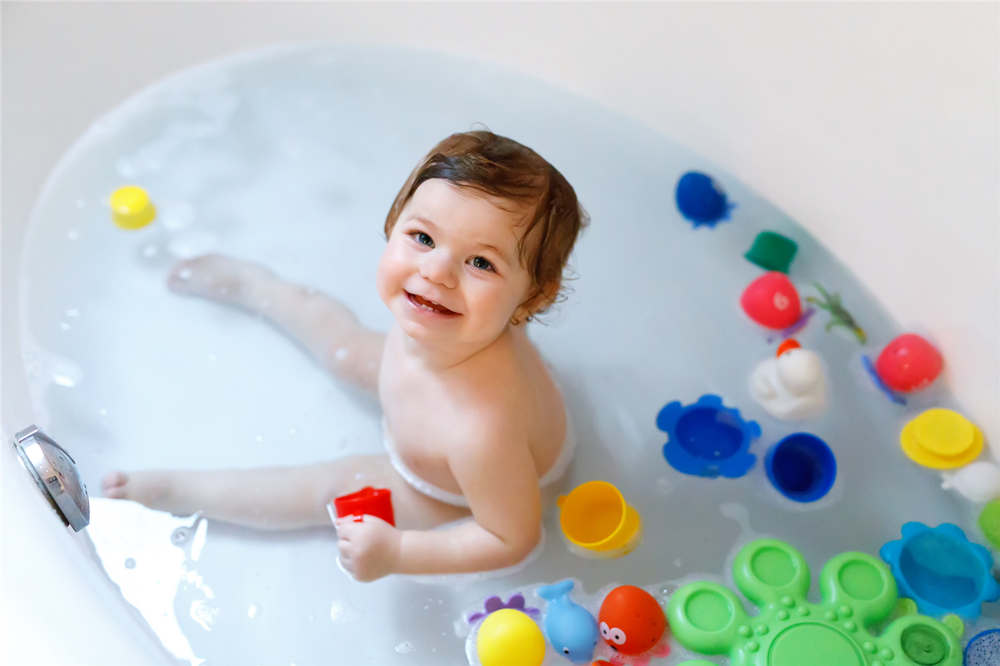 Toddler playing with bath rubber toys