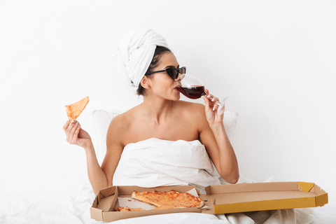 Frau isst Pizz und trinkt Wein vor dem Schlafengehen