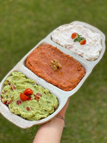 Woman Holding Handmade Ceramic Triple Serving Bowl with Guacamole, Mehammara, and Cheese with Tomatoes