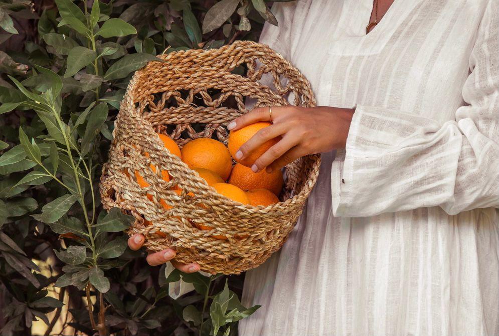 Woman Holding a Halfa Basket Containing Oranges