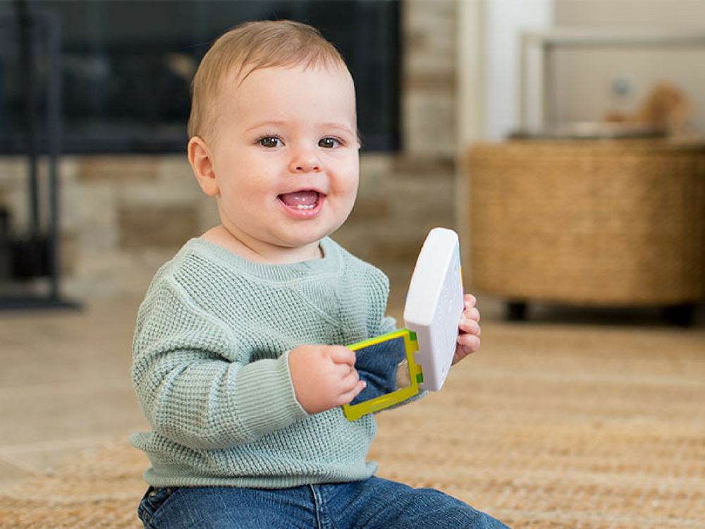 A happy baby plays with an interactive Infantino toy phone