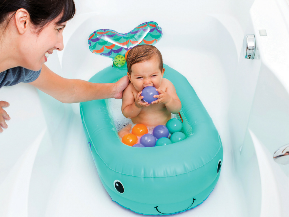 A happy baby takes a bath in his Infantino inflatable whale shaped tub