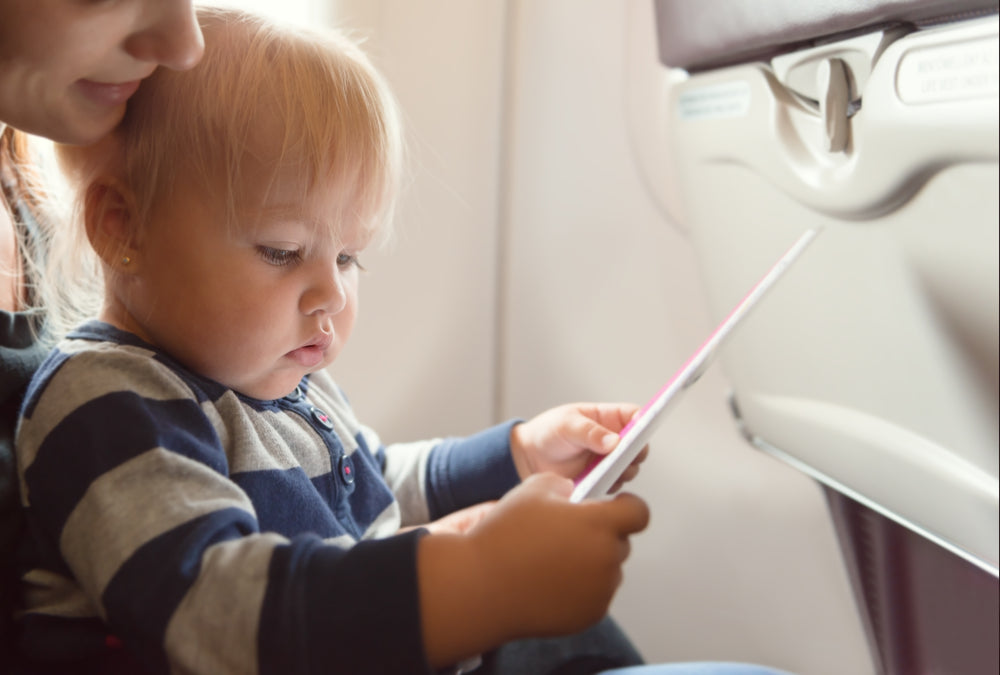 A baby sits in his mothers lap while on a plane