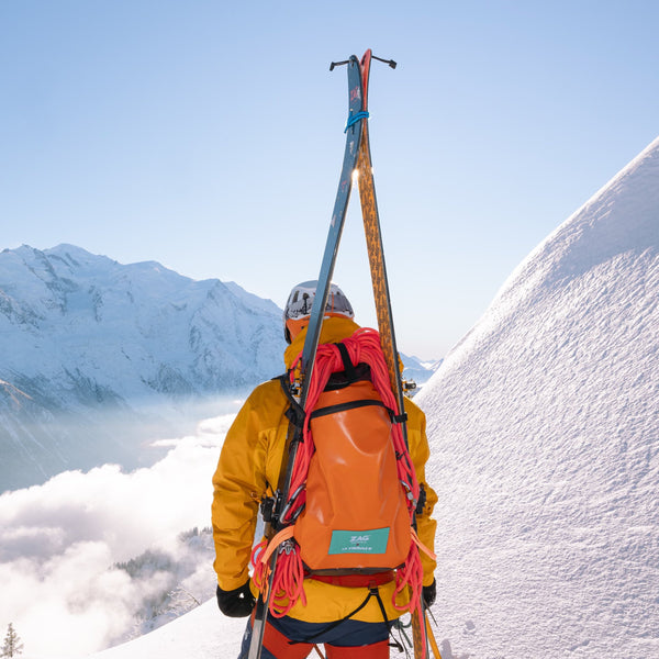 Sac de randonnée La Virgule x ZAG en action dans la montagne, portant ski, cordes, et tout le matériel nécessaire