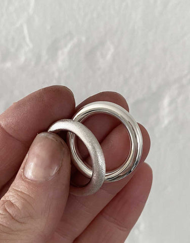 Two silver rings, one with a matte surface and one with a shiny surface.