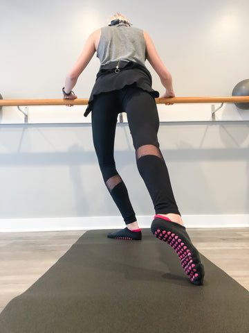 Woman uses her grip socks for barre to perfect her routine.