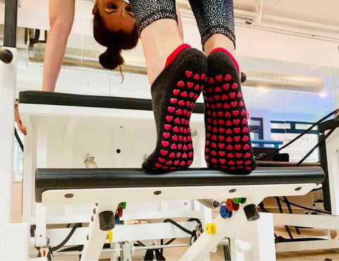 woman wearing grip socks on reformer for safety and deep stretch