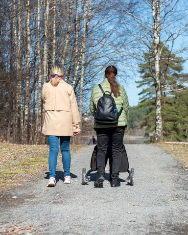 Ryggen til to kvinner. En går med Movu. De går på sti.