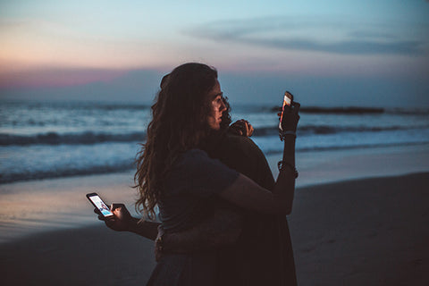 hugging couple distracted on phones