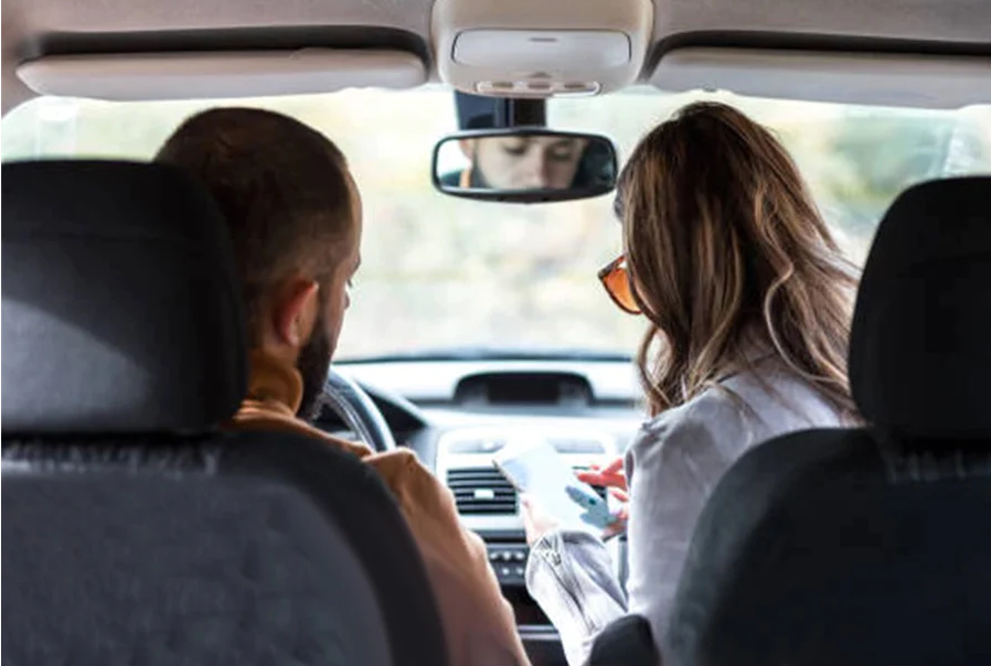 Two people using multiple smartphones in a car