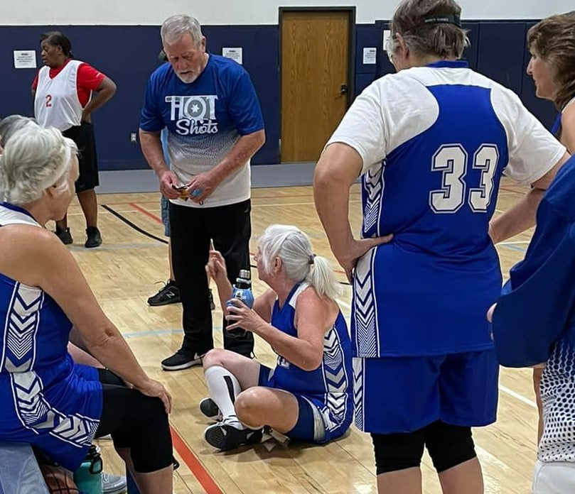 Angela sits on the court as she goes over plays with her team.