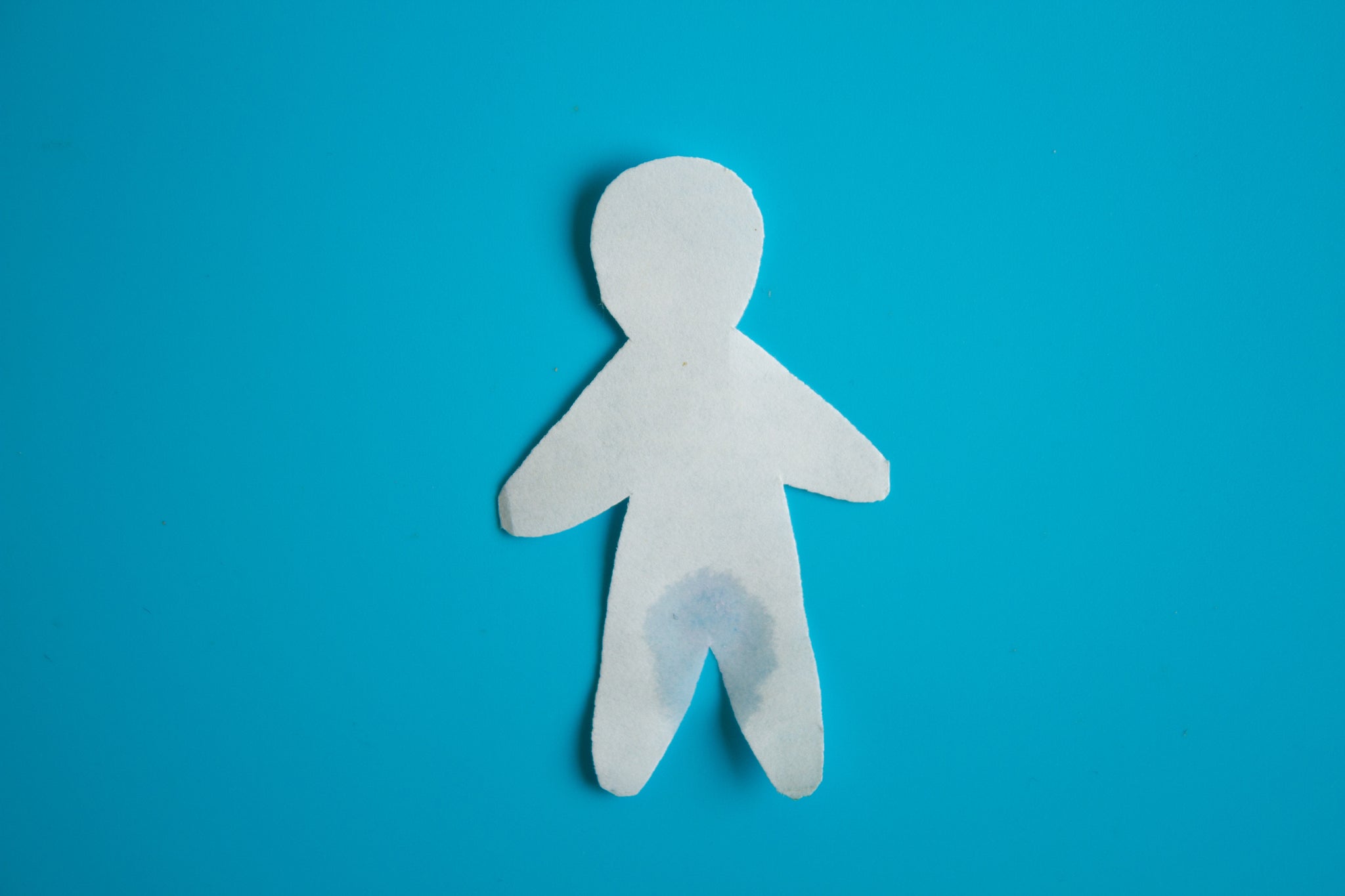 Urinary incontinence concept. Wet paper person. Blue background