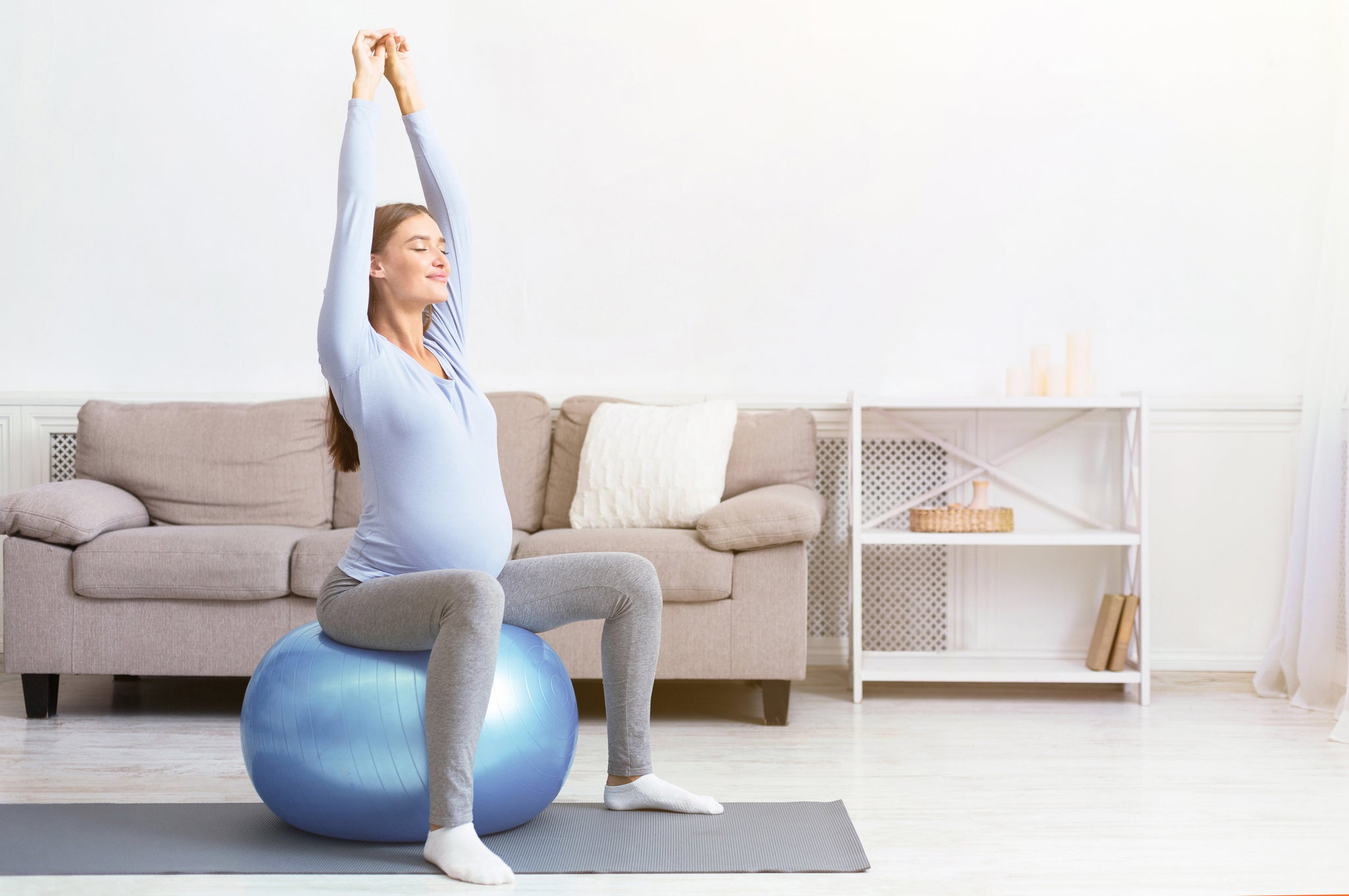 A pregnant woman performs an exercise on a exercise ball.