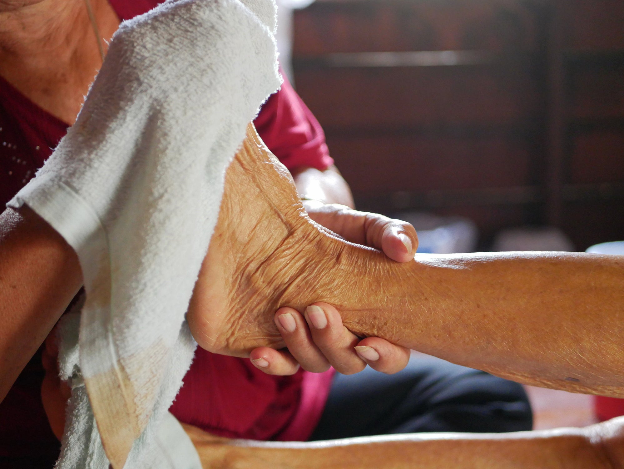 A caretaker washes a patient's foot.