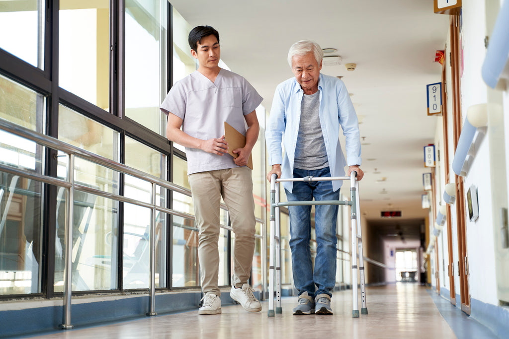 A man walks down a hospital hallway with a walker.