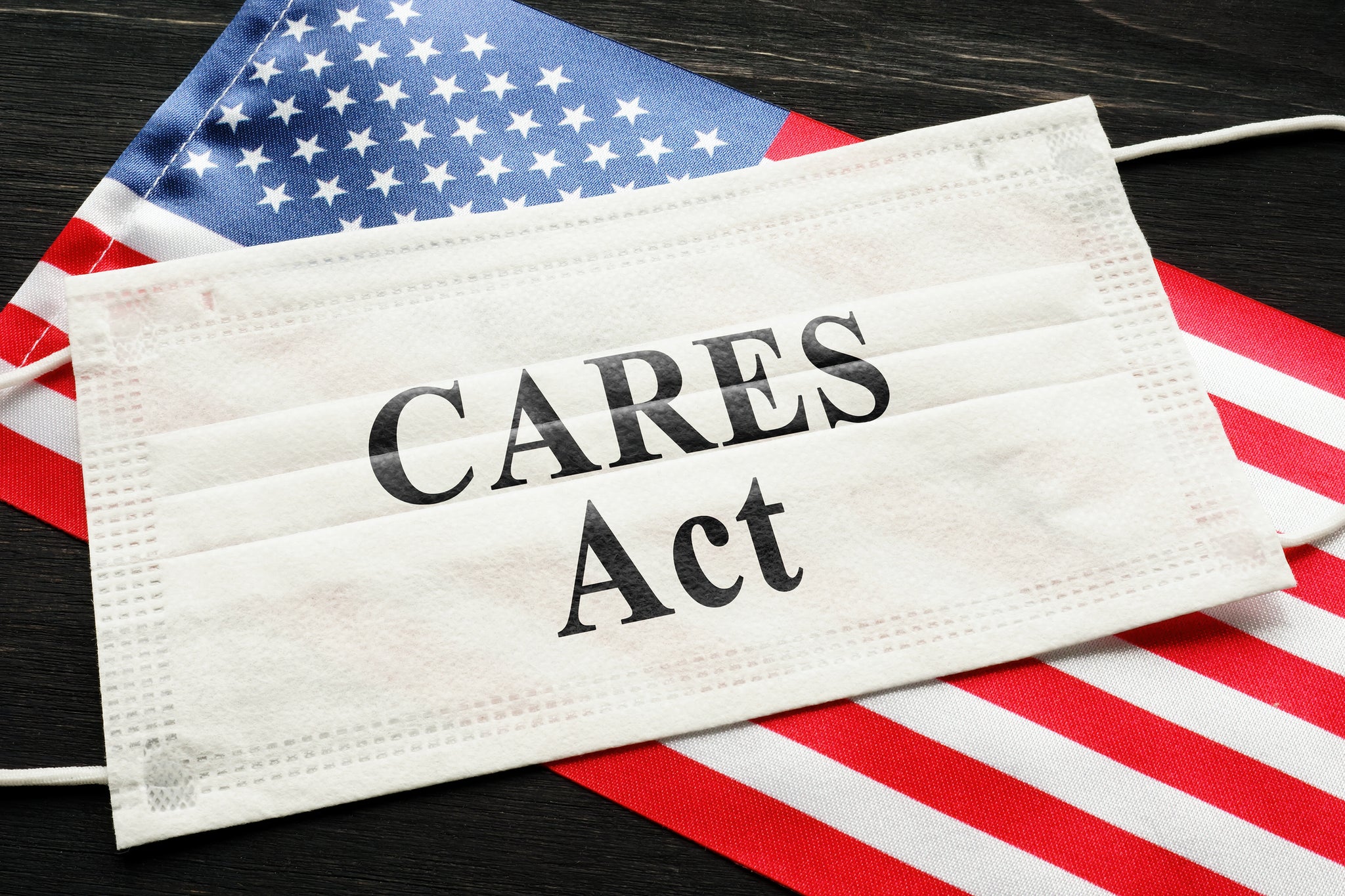A disposable face mask with the words "CARES Act" on top of an American flag.