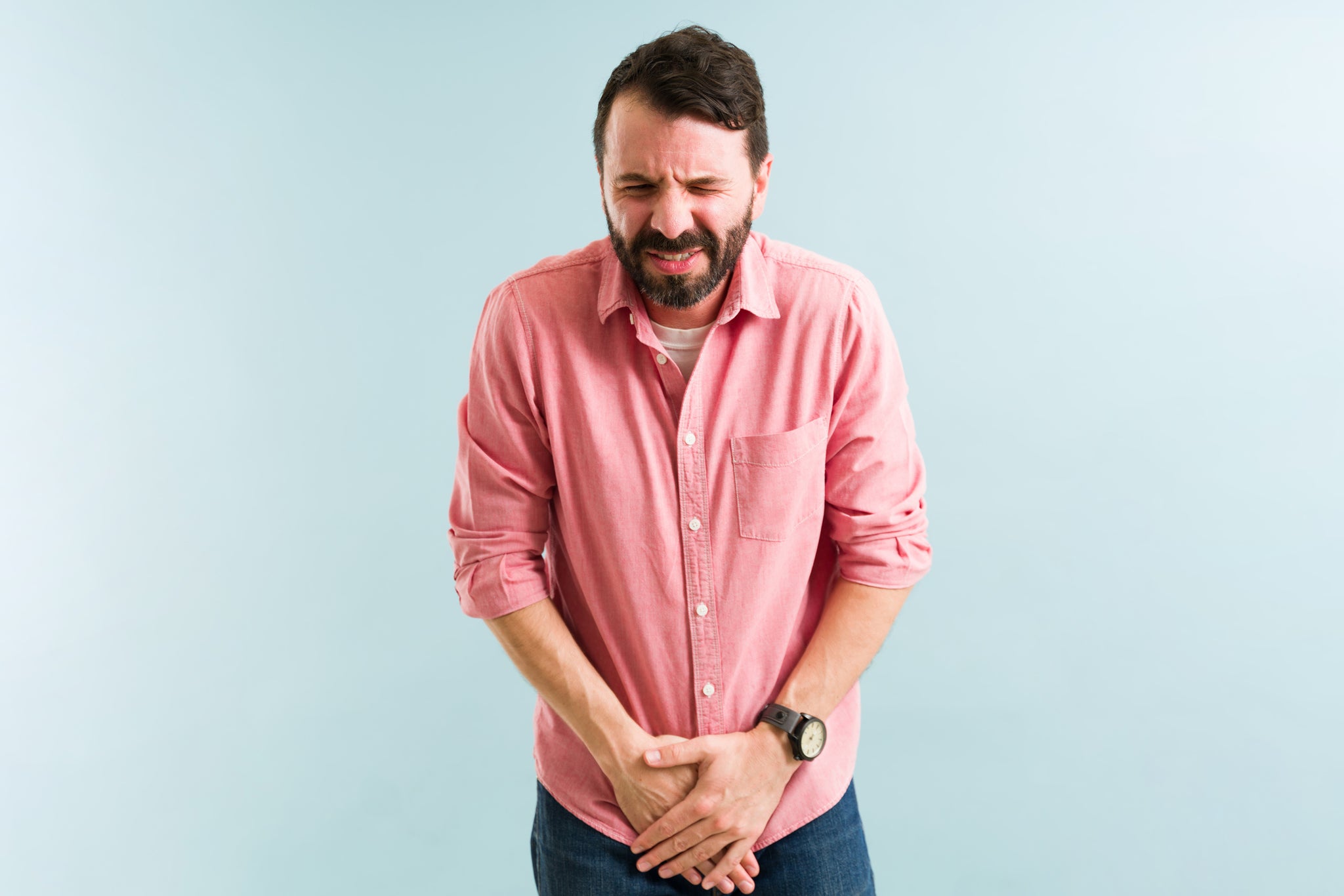 A man holds his pelvic region in pain.