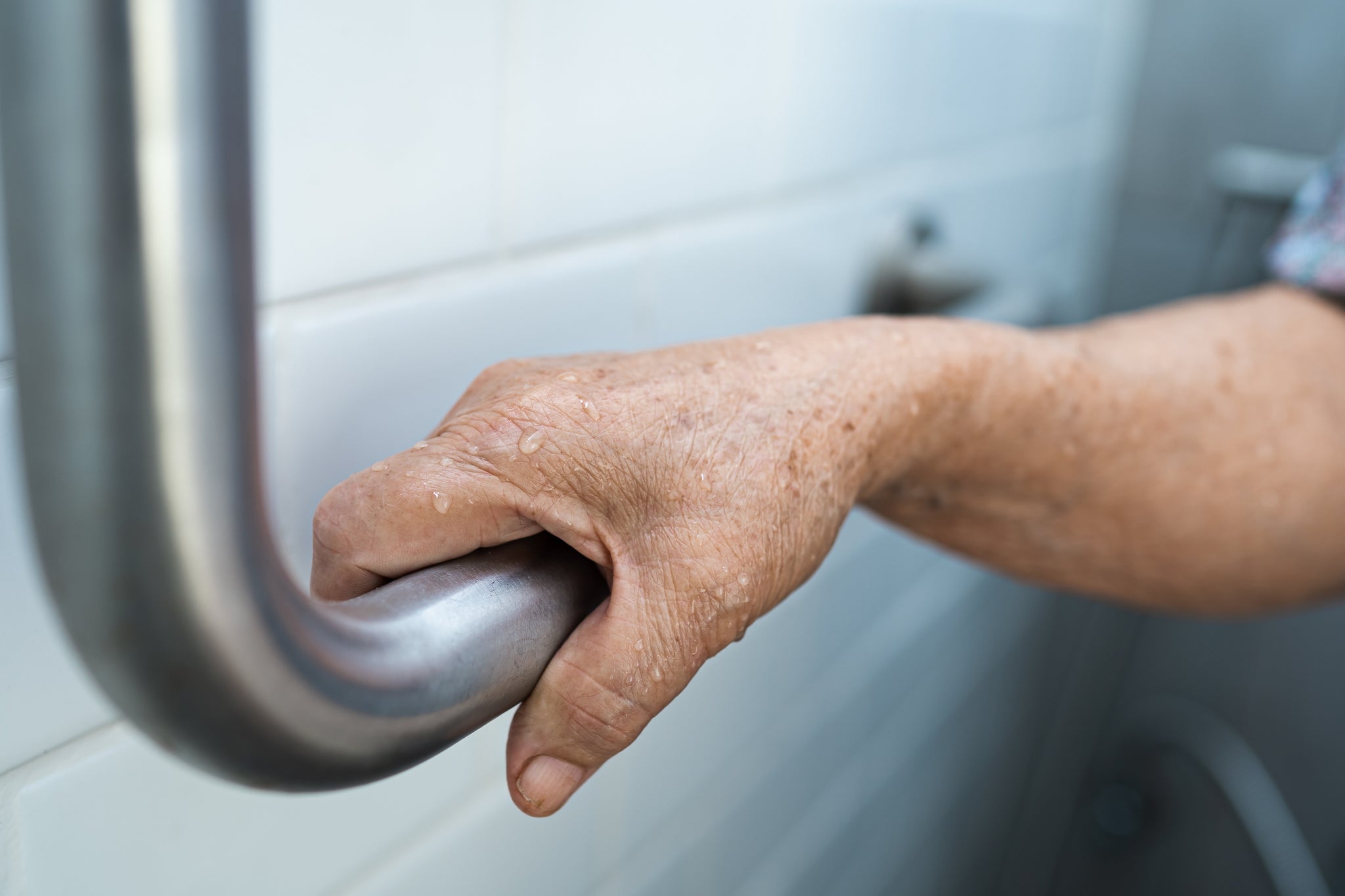 A hand grips a shower rail.