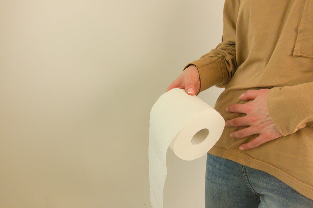 A person walks into frame holding a roll of toilet paper.