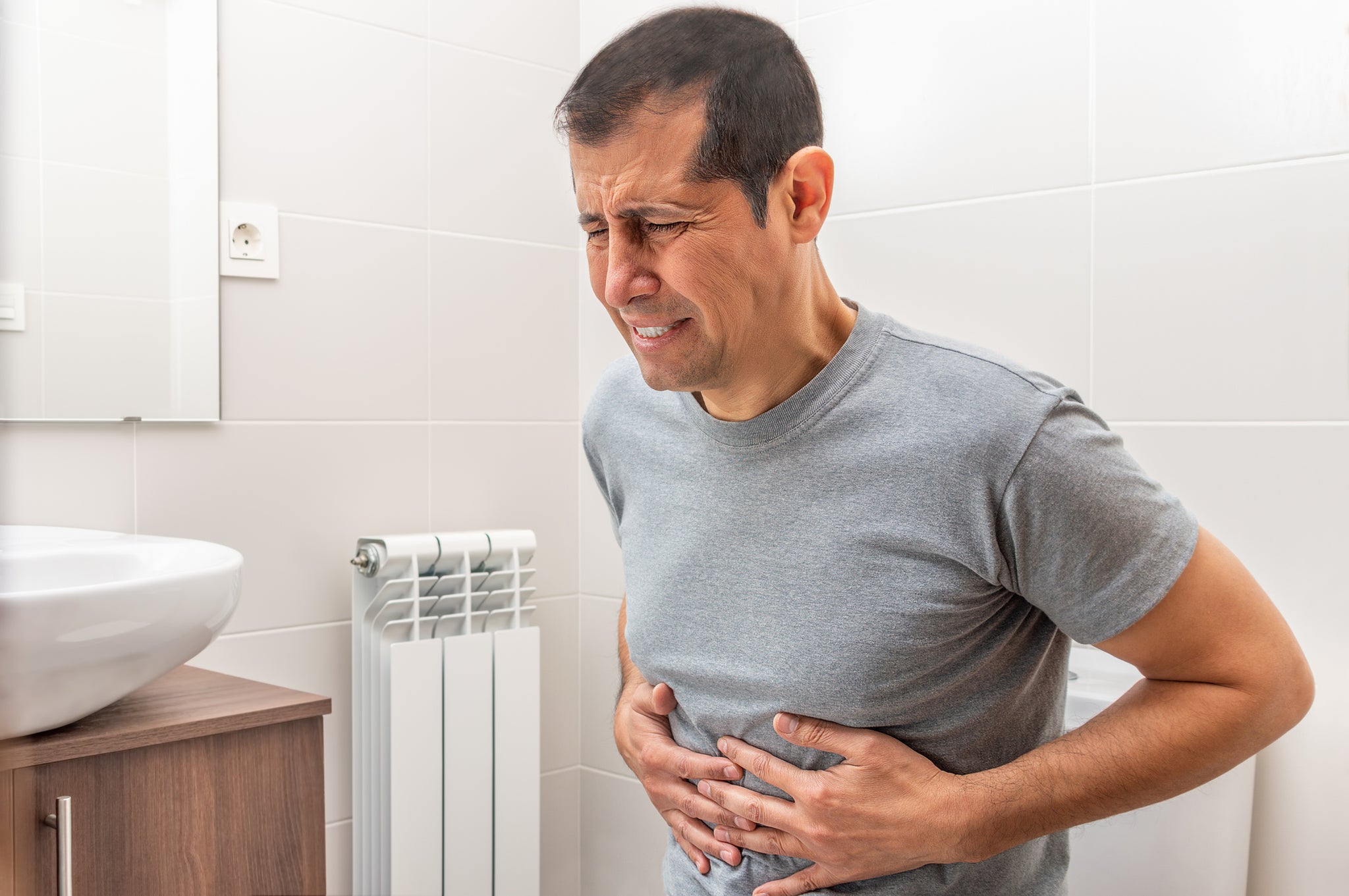 A man grips his abdomen in pain.