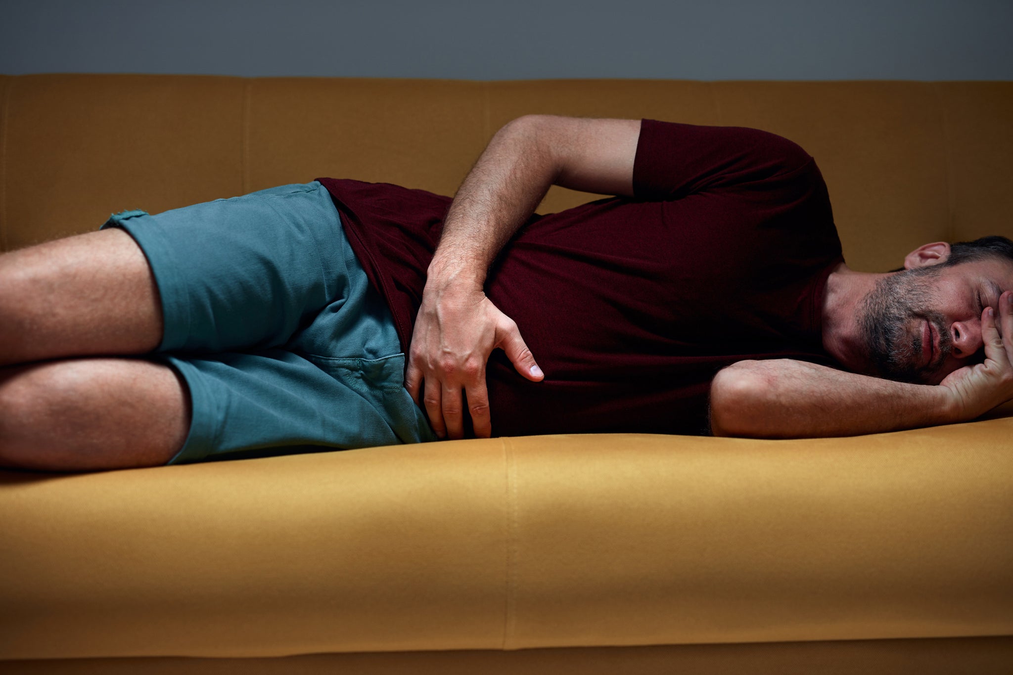 A man lies on a couch with bladder pain.