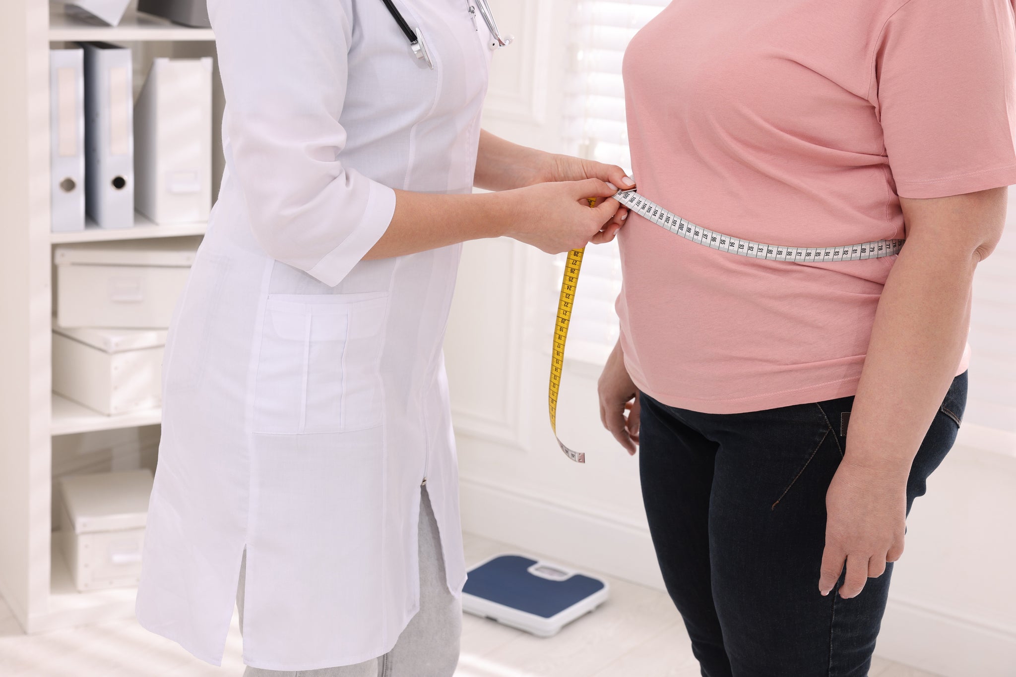 A doctor measures a patients weight loss.