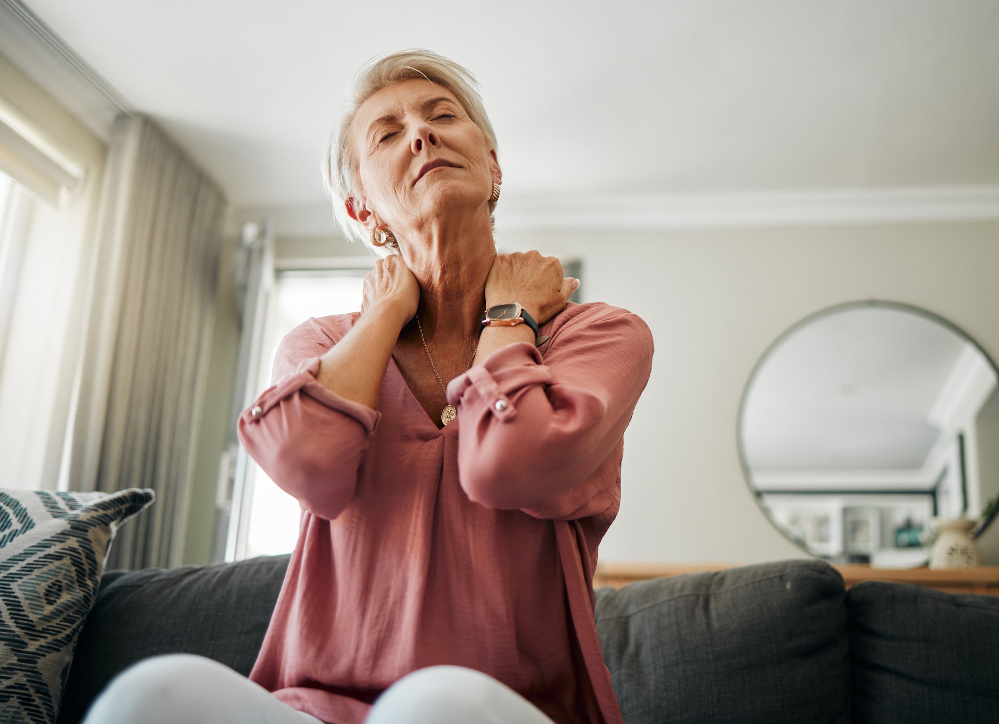 A woman rubs her neck as if she is in pain.