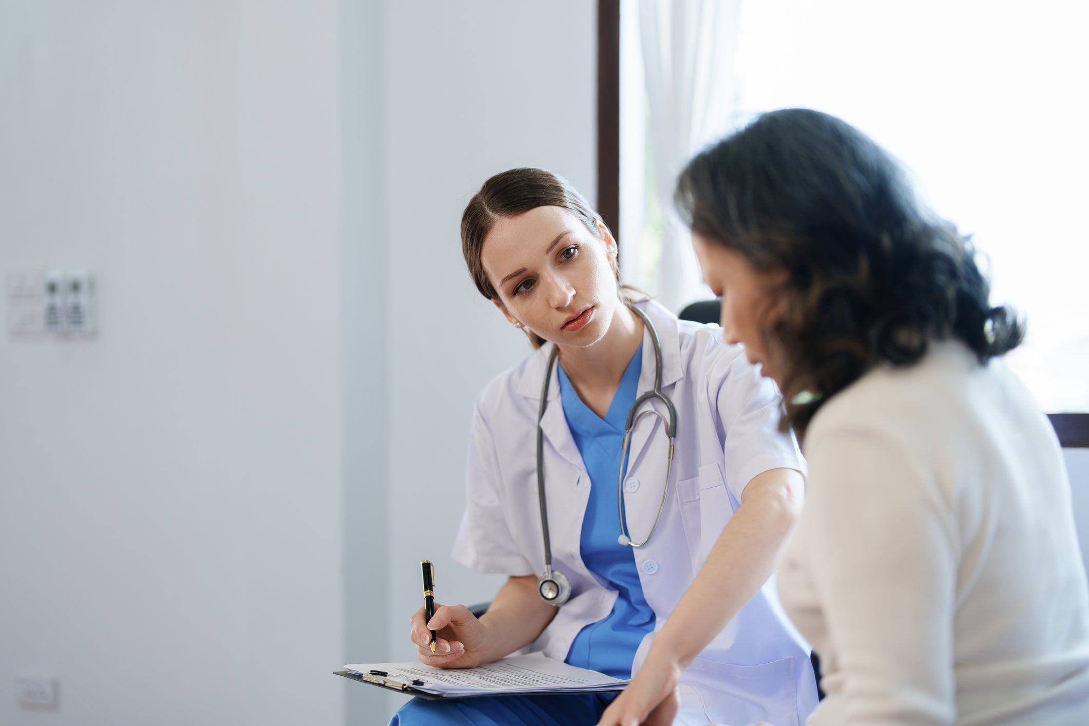 A doctor looks concerned while a patient describes their symptoms.