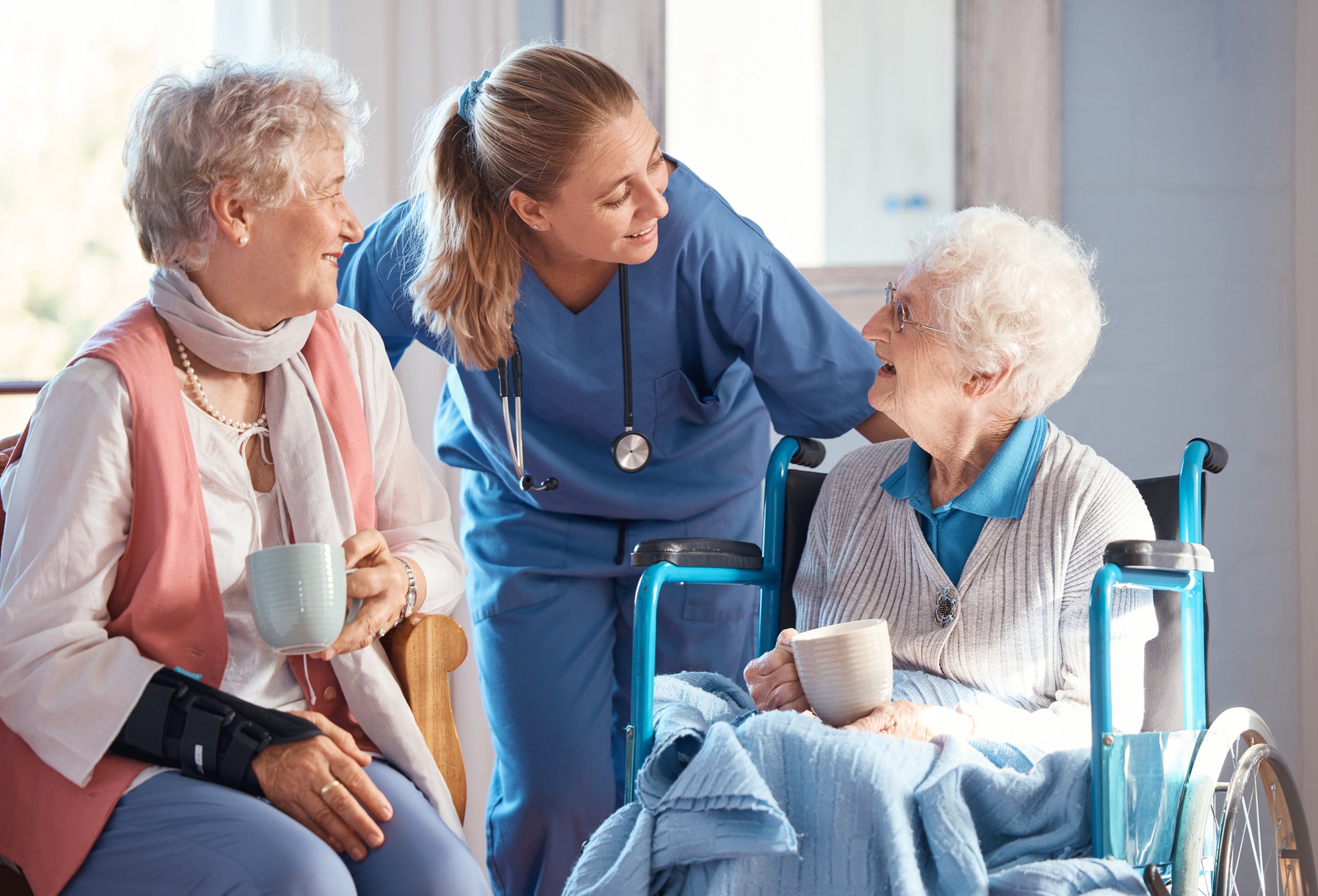 An elderly woman, daughter, and caregiver talk together.