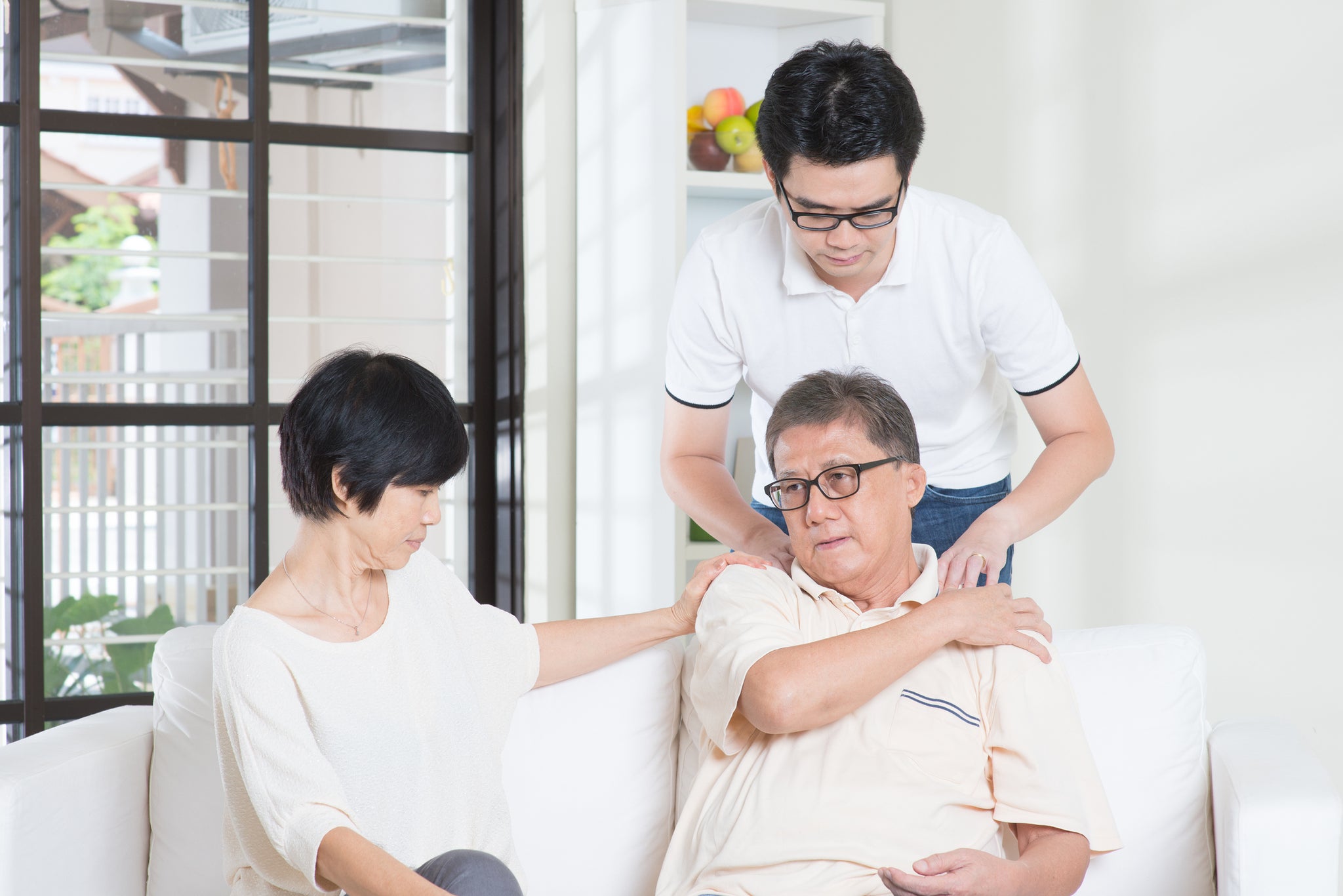 Two family members comfort an older family member.