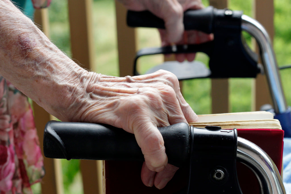 A close up of a person holding  onto a walker with both hands.