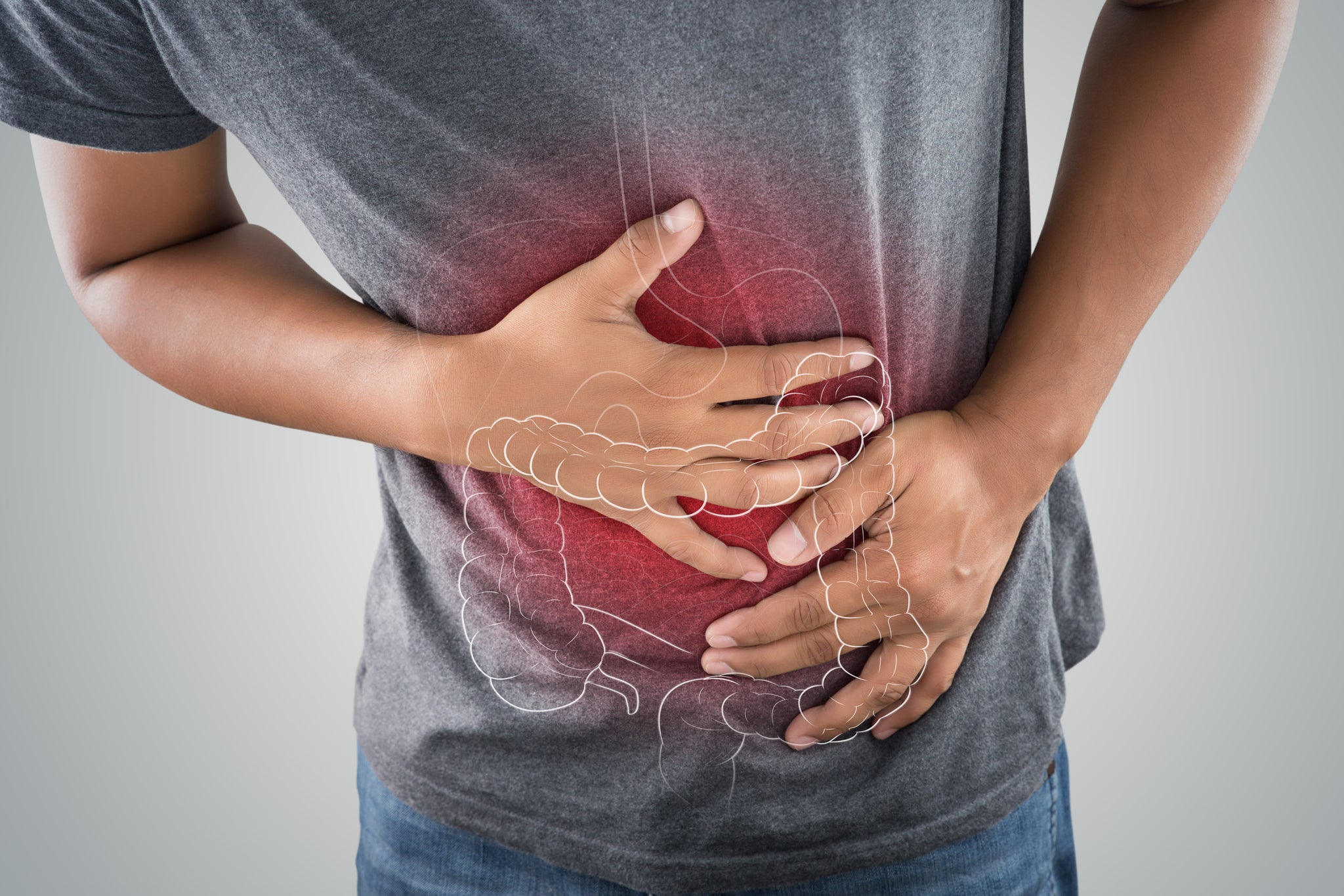 A man clutches his stomach with a graphic overlay of the large intestine.