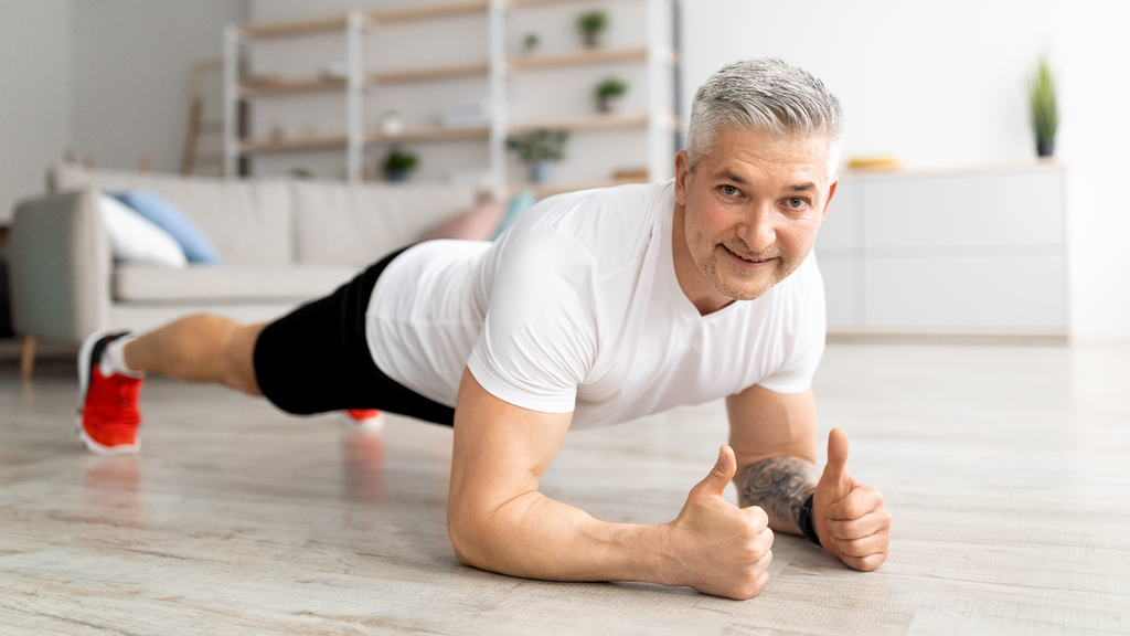 Man with his elbows on the ground and legs straight behind him in a low forearm plank